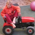 Мальчик в красном на игрушечном тракторе