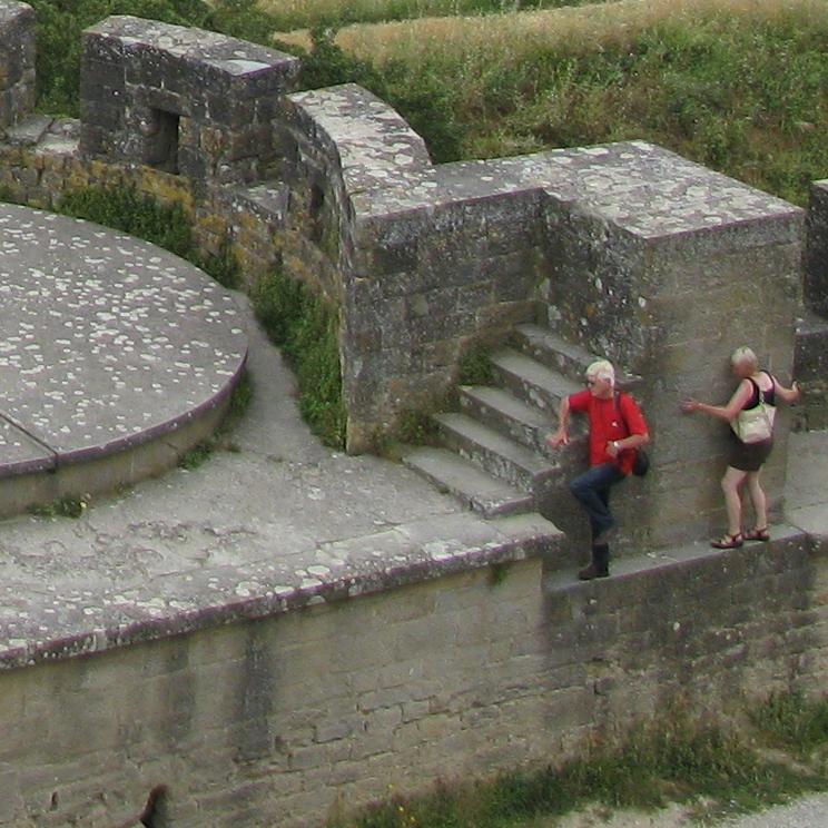 Двое туристов карабкаются по внешней стене замка