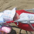 Девочка спит в коляске на пляже